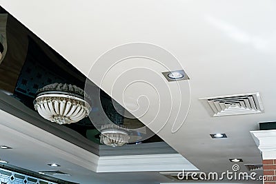 Elegant crystal chandeliers hang on the white ceiling in the lobby of the restaurant. Modern diode lamps inside a retro style lamp Stock Photo