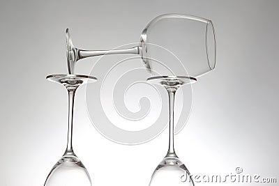 Elegant empty wine glasses with delicate stems arranged neatly, reflecting on a shiny table, set against a minimalist gray Stock Photo