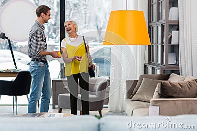 Elegant fancy elderly woman selecting new couch with good-appealing son Stock Photo