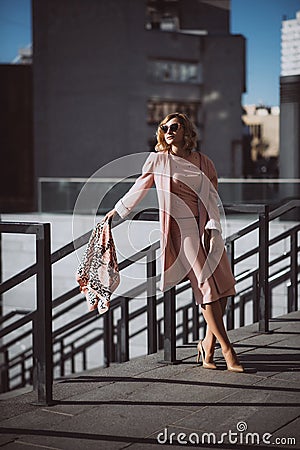 Elegant fashion. Stylish blonde girl in pink clothes and sunglasses posing against a city background Stock Photo