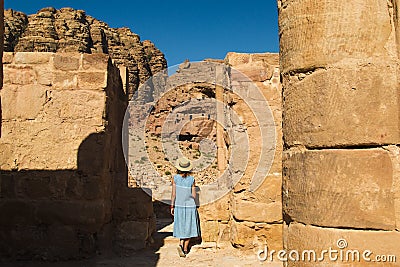 Elegant female tourist in trendy hat and sky-blue dress explore lost rock city Petra. Romantic mood. Atmospheric place. Summer fas Stock Photo