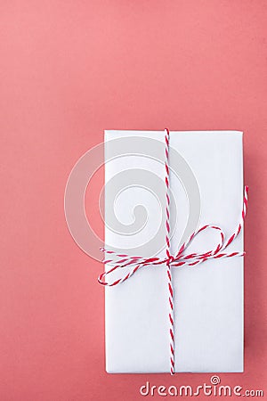 Elegant Gift Box Wrapped in White Paper Tied with Striped Twine on Cherry Pink Background. Christmas New Years Presents Shopping Stock Photo