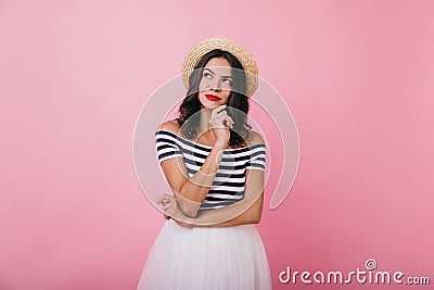 Elegant girl with tanned skin posing with pensive face expression on bright background. Studio phot Stock Photo