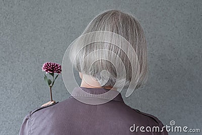 Elegant gray-haired woman holding red flower Stock Photo