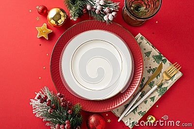 Top view of plates, golden flatware, napkin, wine glass, ornaments, confetti, frosted fir, mistletoe on crimson backdrop Stock Photo