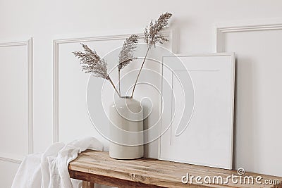 Elegant home interior decor still life photo. Vase with dry reed, grass on old wooden bench. Blank white picture frame Stock Photo