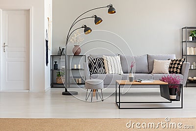 Elegant living room with grey sofa with patterned pillows, wooden coffee table and industrial lam, with Stock Photo