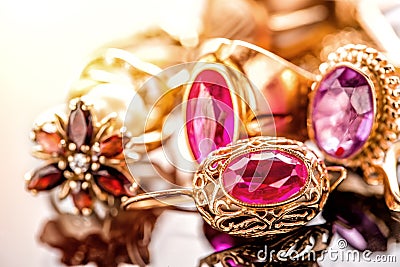 Elegant luxury composition of gold jewelry with ring with red amethyst and ruby gemstone and diamonds on light background close-up Stock Photo