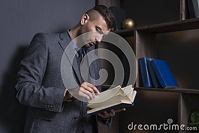 Elegant man in business suit with book. Portrait of handsome stylish man in library. Lawyer reads the book Stock Photo