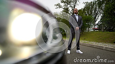 Elegant man in a suit without tie next to a car on the highway Stock Photo