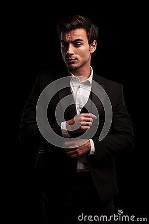 Elegant man in tuxedo and undone bowtie fixing his sleeve Stock Photo