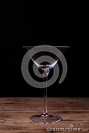 Elegant martini glass on wooden table with black wall background Stock Photo