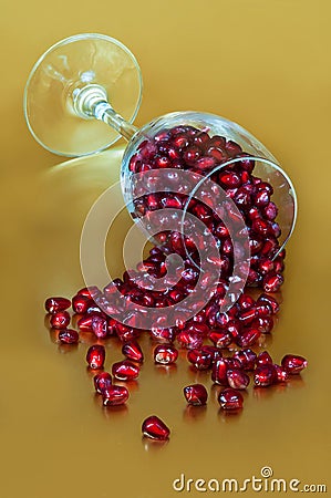 Elegant Pomegranates spilling from wine glass gold background Stock Photo