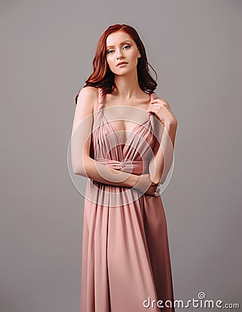 Elegant salmon transformer dress. Beautiful sexy silk evening gown with deep neckline and shoulder straps. Stock Photo