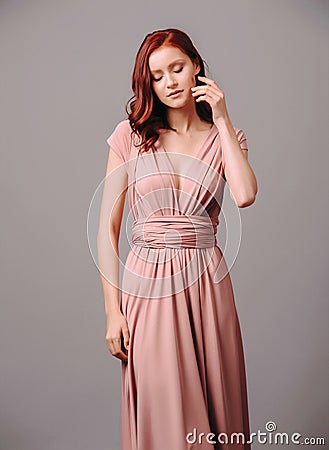 Elegant salmon transformer dress. Beautiful sexy silk evening gown with deep neckline and shoulder straps. Stock Photo