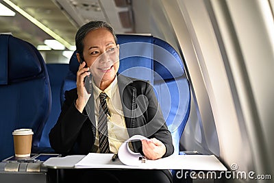 Elegant senior woman negotiating with business partners during business travel flight Stock Photo