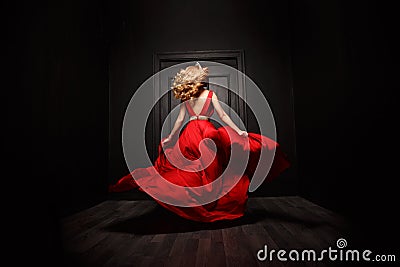 Elegant and woman in the red evening fluttering dress is capture in move, running away from the ceremony Stock Photo