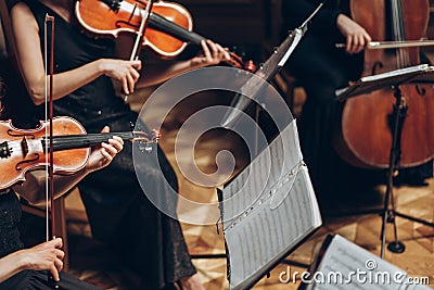 Elegant string quartet playing in luxury room at wedding reception in restaurant. group of people in black performing on violin Stock Photo