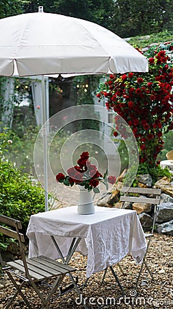 Beautiful serving table outdoor festive holiday with a bouquet roses in a vase. Cottage core yard decorated for a party Stock Photo