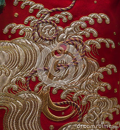 elegant and vibrant red silk fabric with an anchor and waves embroidery texture background close up from a kimono dress Editorial Stock Photo