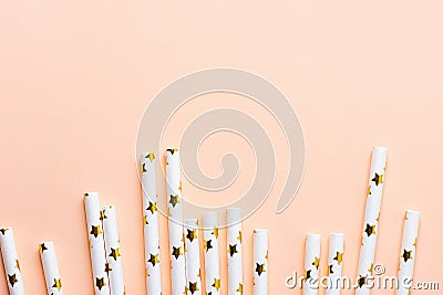 Elegant White Paper Drinking Straws with Golden Stars Pattern Scattered as Border Frame on Pink Peachy Background. Birthday Party Stock Photo