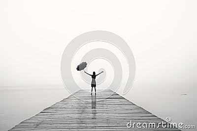 Elegant woman in black rejoices with their arms up in the rain Stock Photo