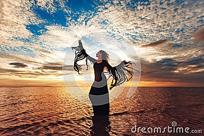 Elegant woman dancing on water. Sunset and silhouette Stock Photo