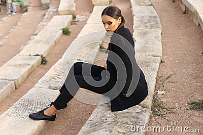 Elegant woman with dark hair wearing a white shirt and black pants Stock Photo