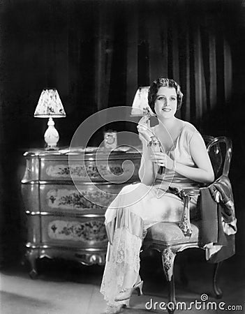 Elegant woman in an evening dress applying perfume to her neck Stock Photo