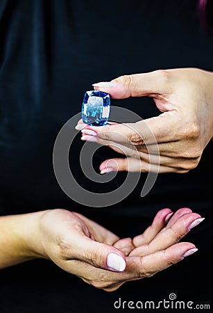 Elegant woman`s hands hold a large deep blue topaz stone Stock Photo