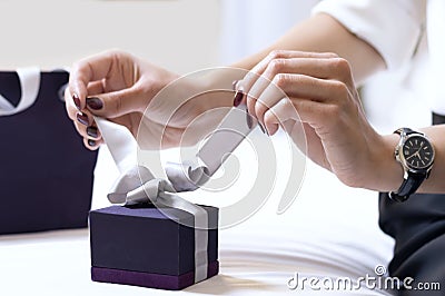 Elegant woman`s hands unleash a bow on a gift box. The concept of a holiday, congratulations and love. Stock Photo