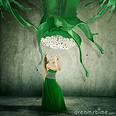 Elegant woman using an umbrella to shelter from color splashes falling down Stock Photo