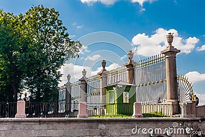 Elegant wrought-iron fence adorned with vases and gilded details built around Summer Garden Park Editorial Stock Photo