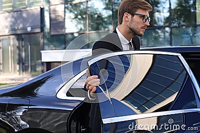Elegant young businessman entering his car while standing outdoors Stock Photo