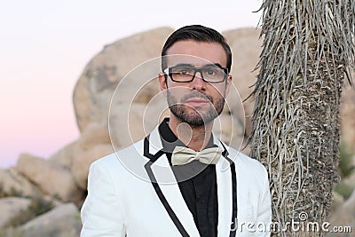 Elegant young fashion man with glasses in tuxedo shot at sunset in Joshua Tree National Park, California, USA Stock Photo
