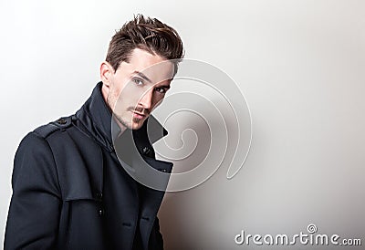 Elegant young handsome man in long stylish dark blue coat. Studio fashion portrait Stock Photo