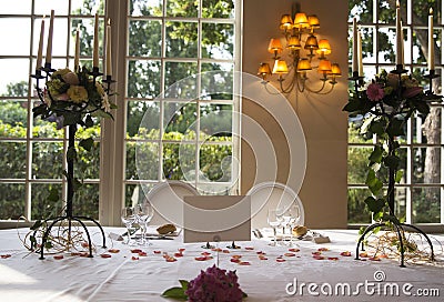Elegantly served with wedding glasses, cutlery and decorated with flowers tables with white tablecloths and burning candles Stock Photo