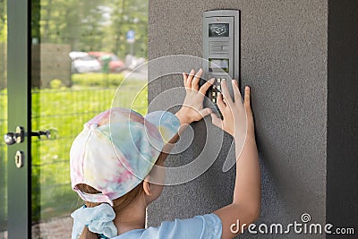 Elementary school age child, girl using a door entry phone, entering the entry code alone outdoors, block of flats Stock Photo