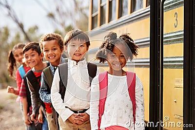 Elementary school kids queueing to get on to a school bus Stock Photo