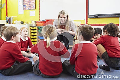 Elementary School Pupils Telling Story To Teacher Stock Photo