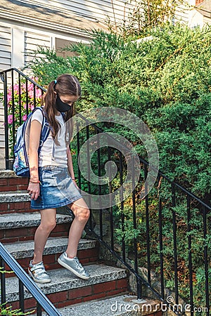 Elementary school student in a cloth dust mask with backpack in the street. Preteen girl is going to school in new Stock Photo