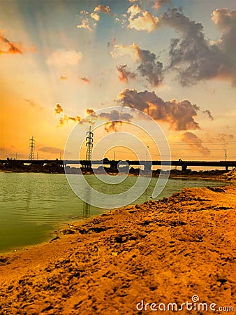 Elements of Serenity Clouds, Bridge, Lake, and Electric Tower Paint a Peaceful Landscape. Stock Photo