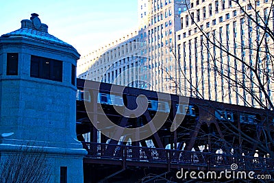 Elevated train travels over Chicago River and riverwalk on frigid January morning. Stock Photo