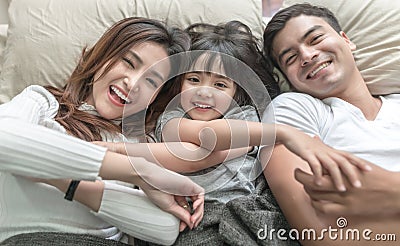 Elevated view portrait of happy family lying on bed and looking up and holding hands. Stock Photo
