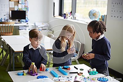 Elevated view of three primary school kids working together using construction blocks in a classroom Stock Photo