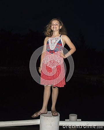 Eleven year old girl standing on a post at night Stock Photo