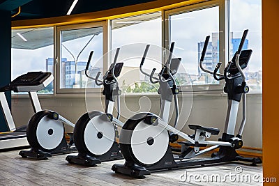 Moscow, Russia, 10.10.2019, Elliptical trainers standing in a row, gym with windows, view of the whole city Editorial Stock Photo