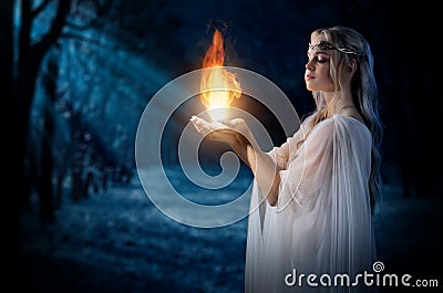 Elven girl holding fire in palms at night forest Stock Photo