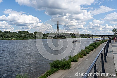 Embankment of the Vistula River in Warsaw. The ship is sailing. View of the bridge and the stadium. Sky with clouds. Editorial Stock Photo