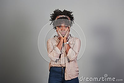 Embarrassed african american girl keep her hands to the face while stands at grey background Stock Photo
